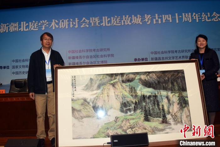 开幕式上，陈星灿(左)代表中国社会科学院考古研究所接受新疆昌吉州赠送的绘画作品?！∷镒苑?摄